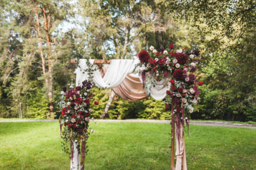 Wedding ceremony in rustic style decorated with different red fl