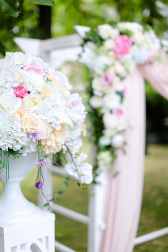 Close up bouqet of flowers near wedding arch in park.