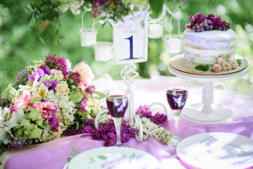 Table number one with bouquet of violet flowers and little cake